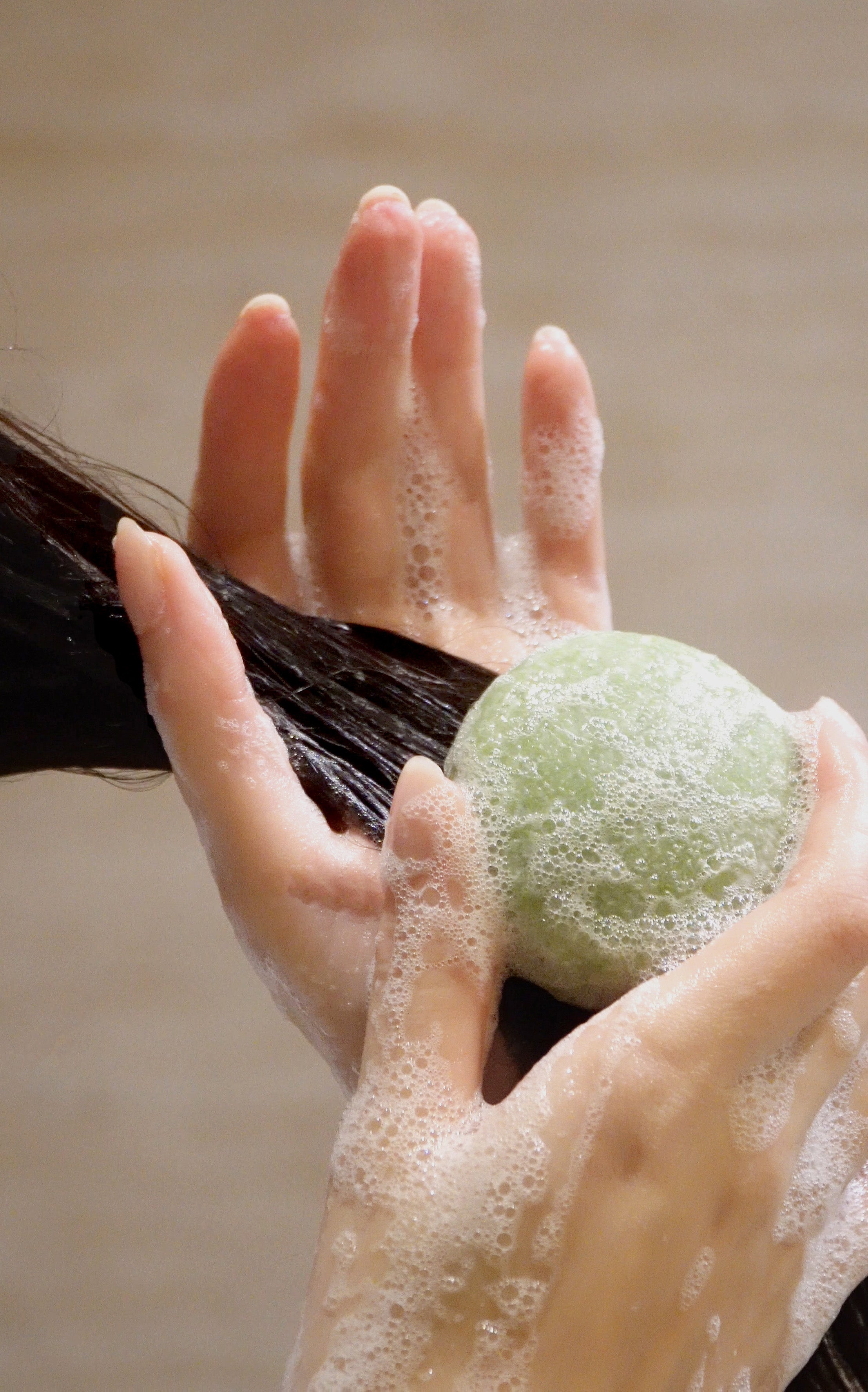 Manos sujetando champú sólido Ellie's Land siendo usado sobre pelo